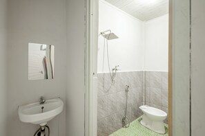 Un baño con lavamanos blanco, espejo, ducha e inodoro.