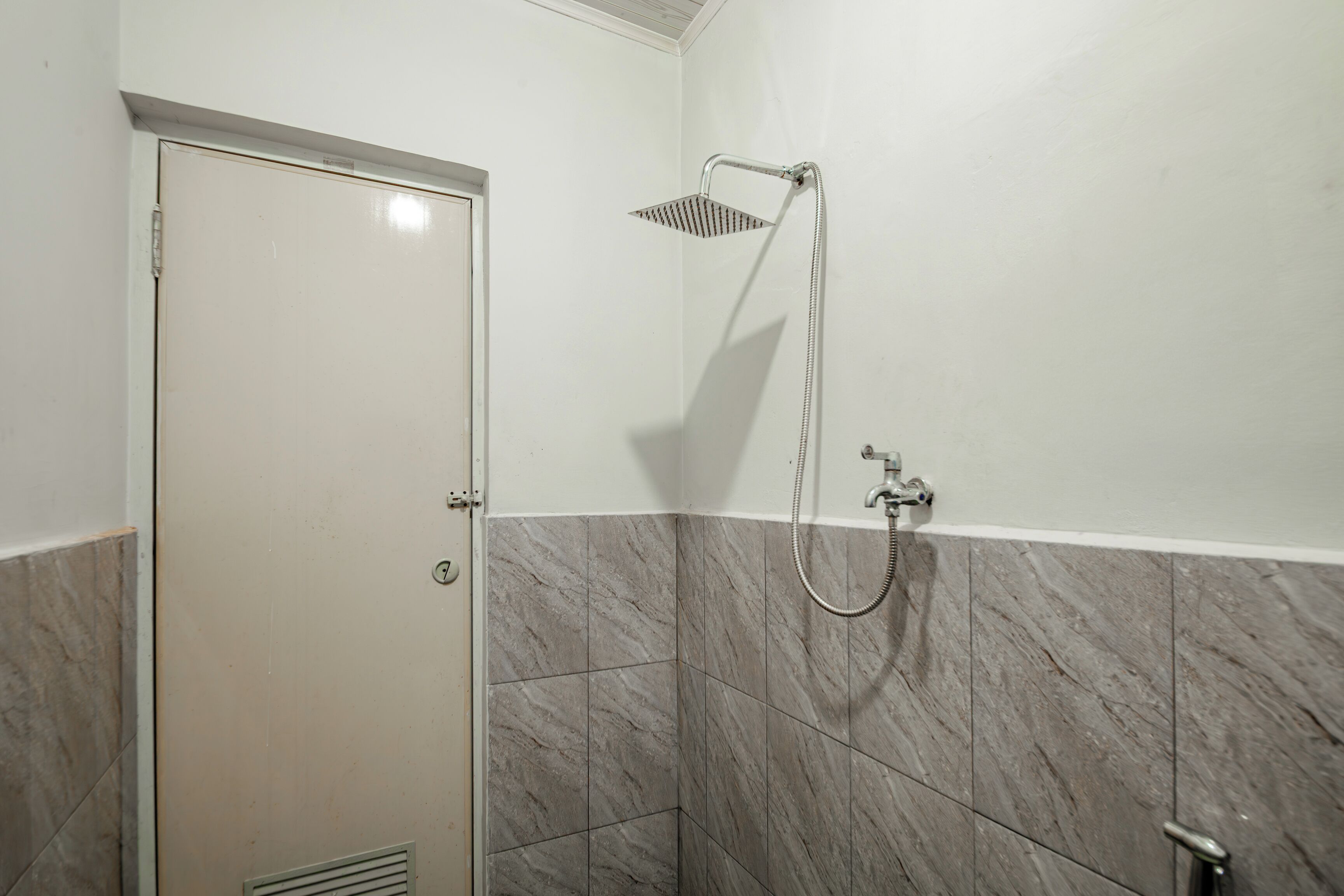 Un baño con ducha, una puerta y paredes de azulejos.