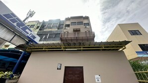 Un edificio con una puerta marrón, un letrero que indica la habitación número 218, y una vista parcial de una estructura azul a la izquierda.