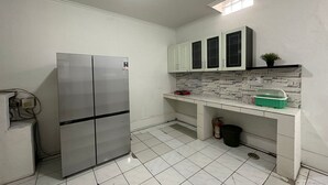 Cocina compacta con armarios blancos, refrigerador empotrado y salpicadero de azulejos.