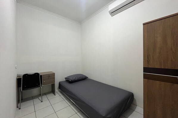 A small, clean room with a single bed, a desk with a chair, and a wardrobe.