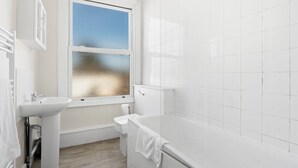 A modern bathroom with a white sink, toilet, and bathtub. - TTSA - Essential 1 Bedroom Apartment 2 - Croydon (Croydon)