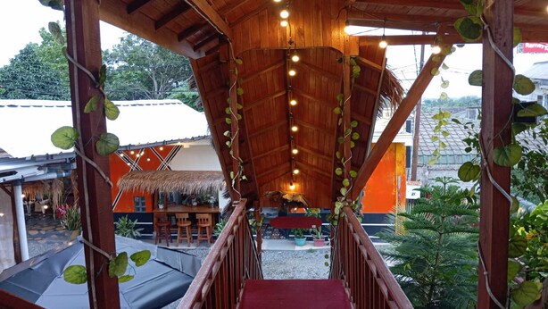 A wooden staircase leading to a covered area with hanging lights and potted plants.