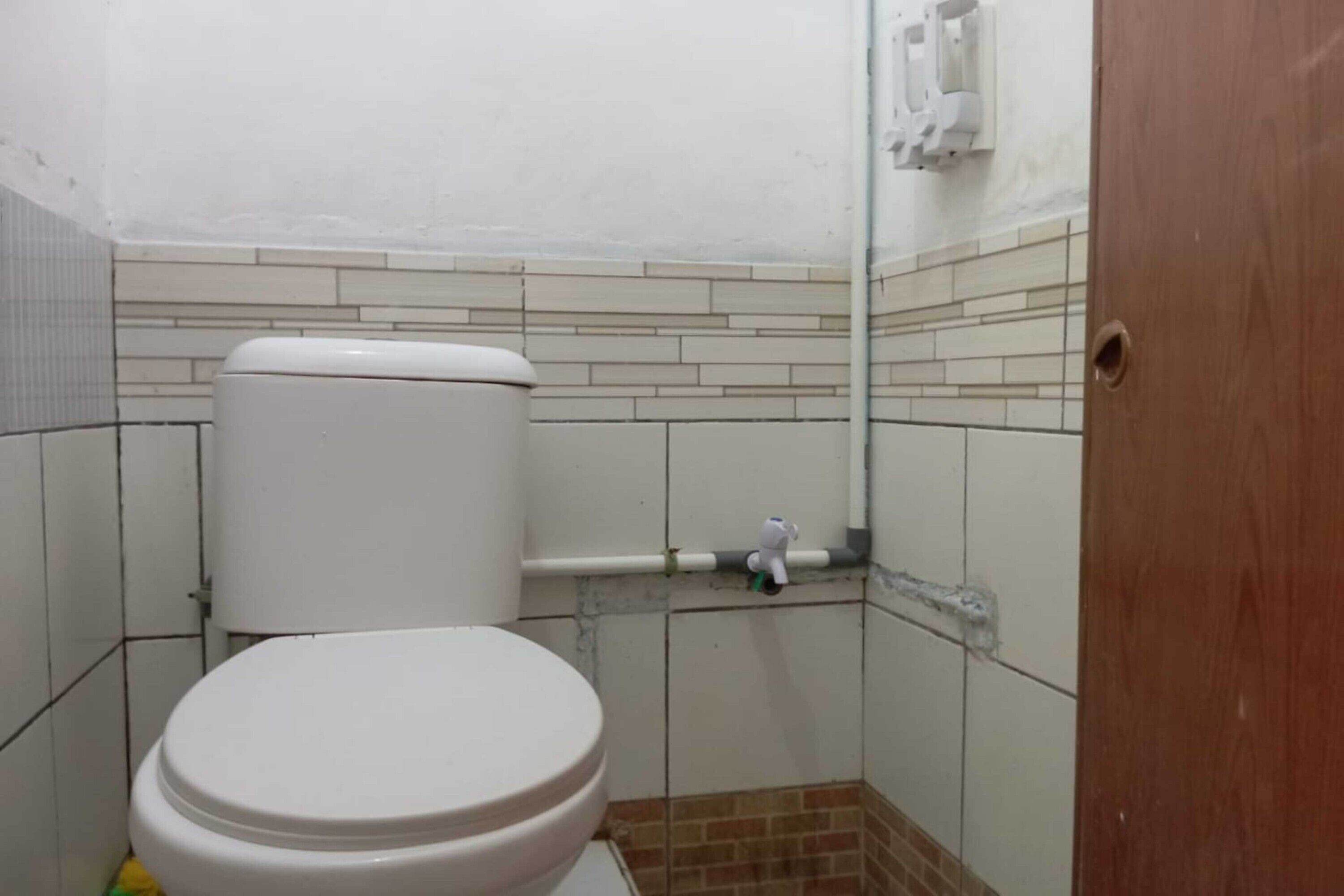 A small, tiled bathroom with a toilet, a hand dryer, and a wall-mounted soap dispenser.