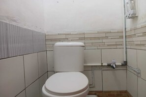 Ein kleines, kompaktes Badezimmer mit Toilette, Waschbecken und Duschbereich.