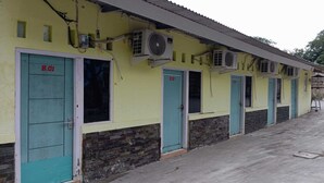 A row of rooms with teal doors and a yellow exterior, each with an air conditioning unit mounted above the door. - OYO 93631 Eltsania Exclusive Homestay Syariah (Bandar Lampung)