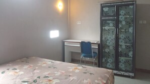 A room with a bed, a desk, a chair, and a wardrobe with floral patterns. - Hotel O Rumah Singgah Cemara Syariah (Pekanbaru)
