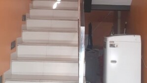 A staircase leading to a room with a white appliance, possibly a refrigerator, and a wall-mounted device. - Hotel O Rumah Singgah Cemara Syariah (Pekanbaru)