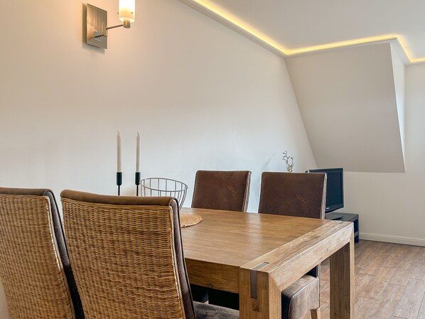 Un coin repas avec une table en bois, des chaises en osier et un luminaire moderne.