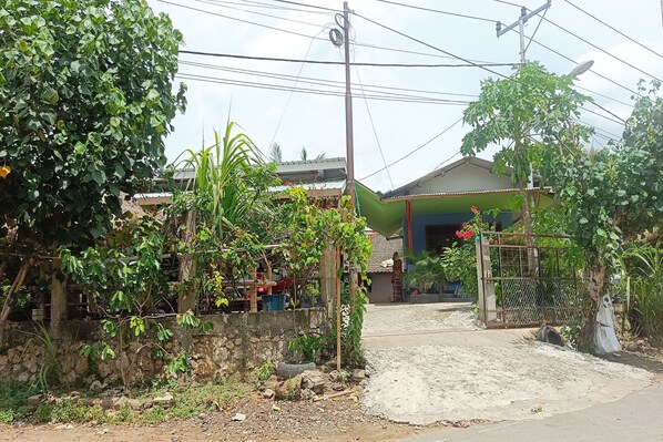 A residential area with a house, a gate, and a dirt path. - Hotel O Lotus Guest House (Tetebatu)