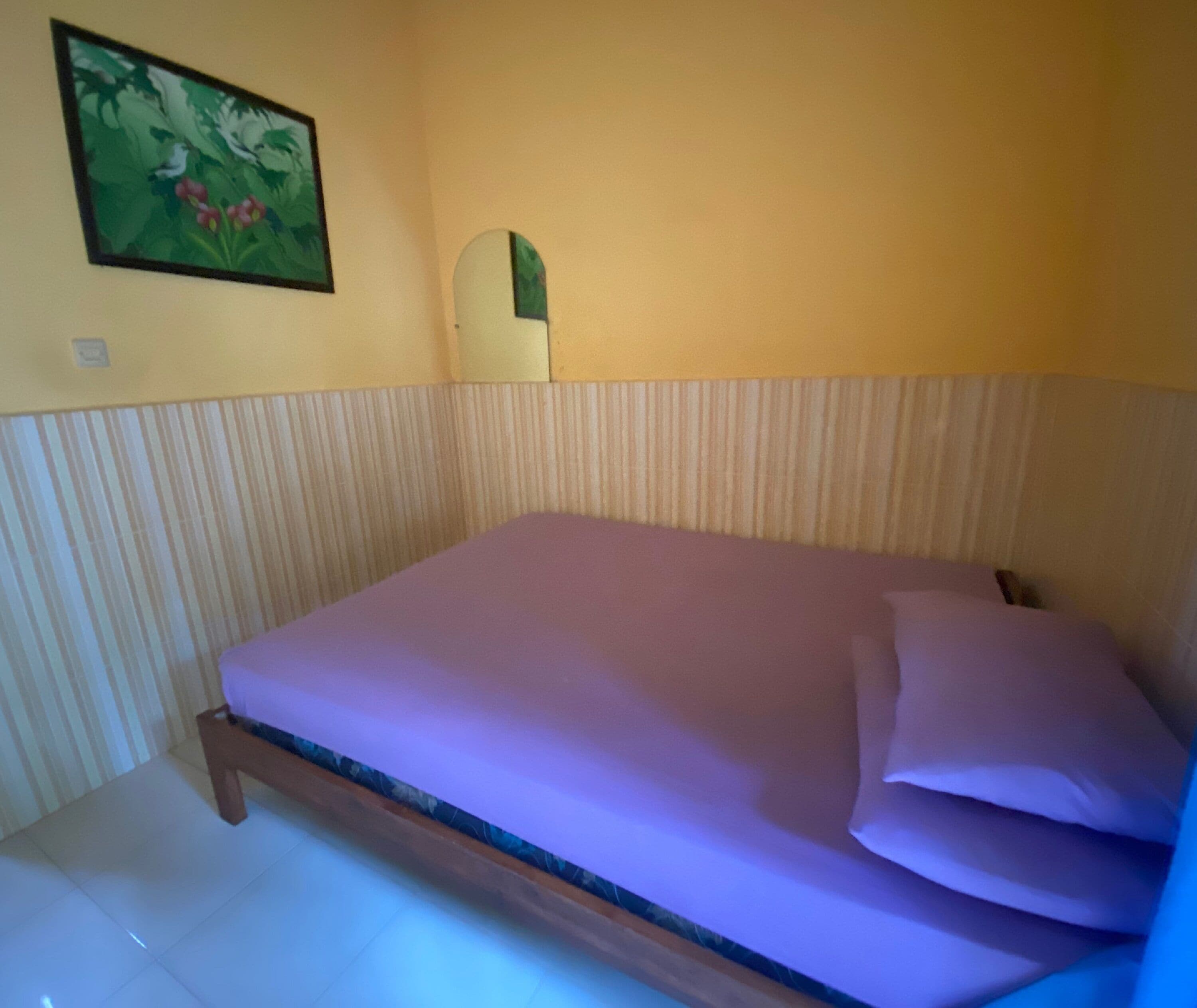 Una habitación con una cama, un cuadro en la pared y un panel decorativo a rayas.