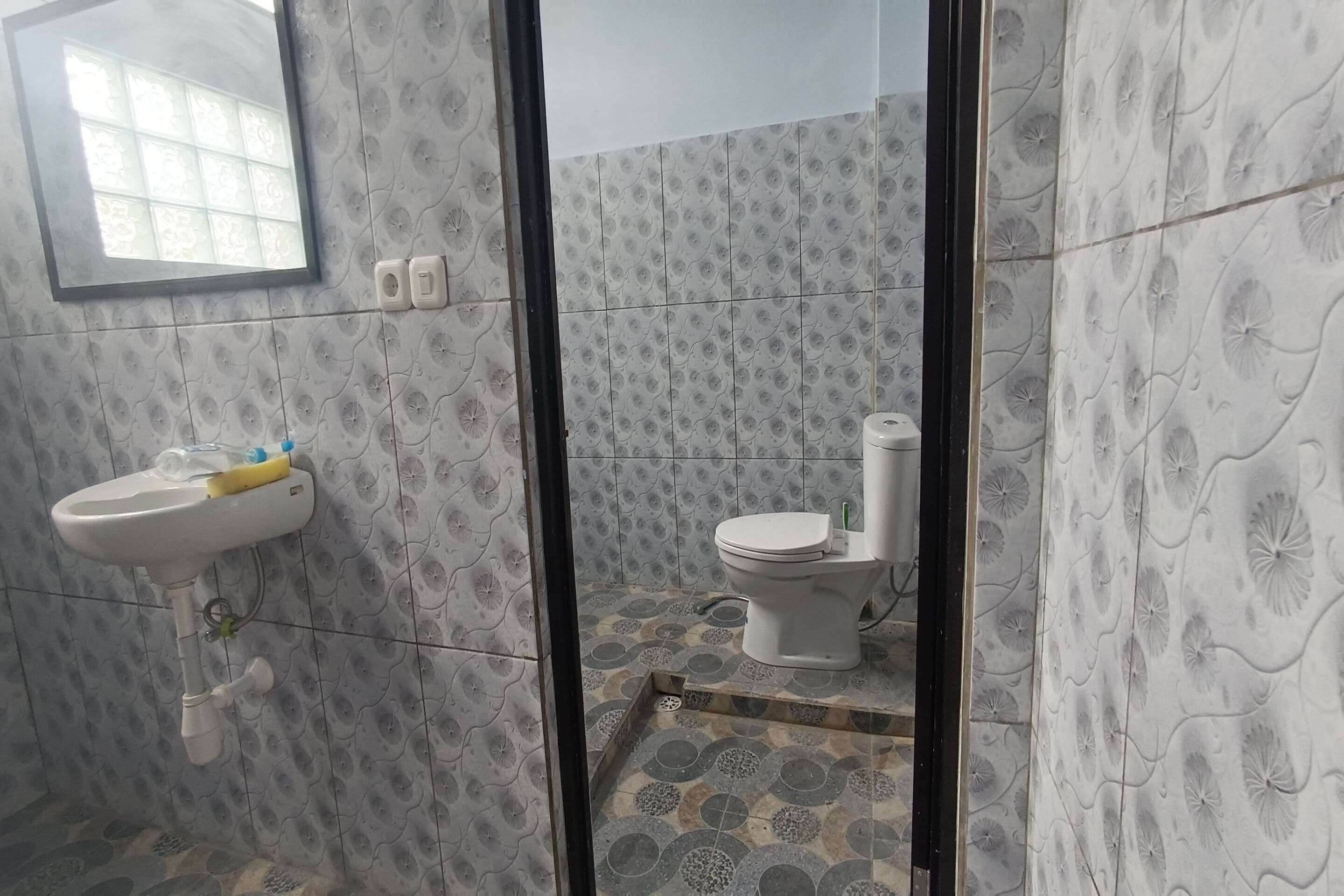 A bathroom with a sink, toilet, and patterned tiles.