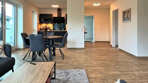 Ein modernes Wohnzimmer mit Couch, Esstisch und Stühlen sowie einem Holztisch.