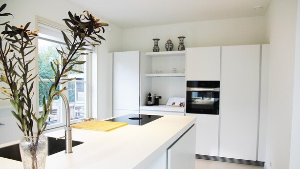 Een moderne keuken met witte kasten, een centraal eiland en een inbouwoven.