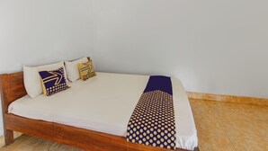 A single bed with a wooden frame, white bedding, and two decorative pillows with geometric patterns. - Hotel O Kaila Guesthouse (Kotaraja)