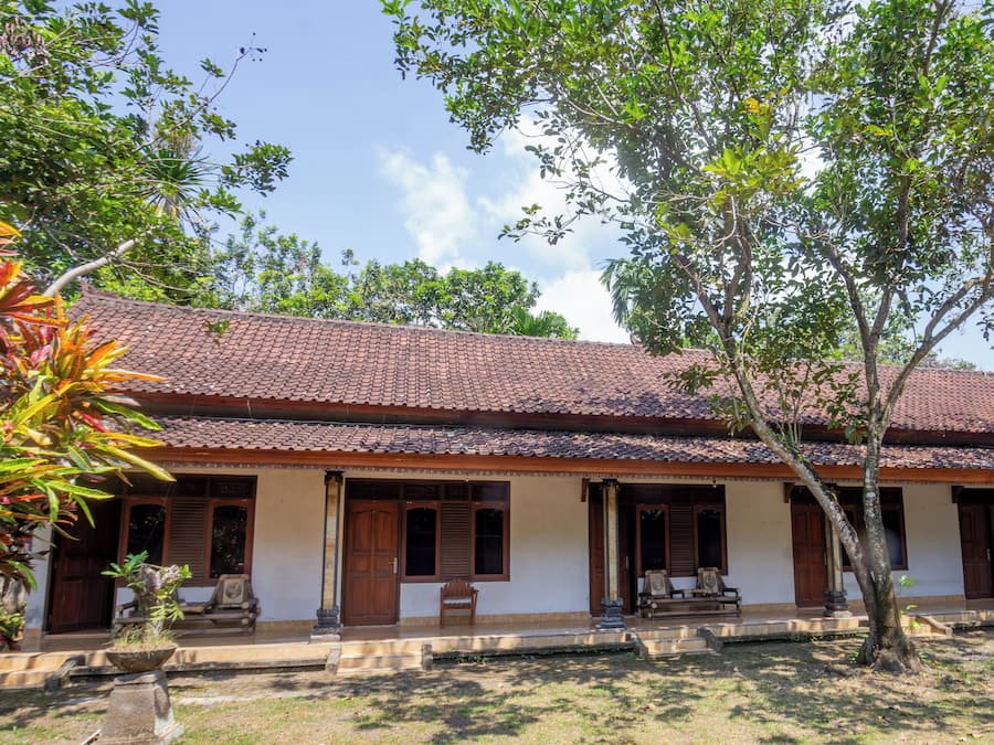 A traditional building with a tiled roof, wooden doors, and a porch with benches.