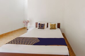 A bed with a white mattress, a blue and yellow patterned blanket, and two pillows with yellow and blue patterns. - Hotel O Kaila Guesthouse (Kotaraja)