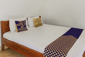 A bed with a white mattress, two pillows with geometric patterns, and a purple blanket with a polka dot design. - Hotel O Kaila Guesthouse (Kotaraja)