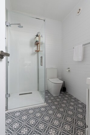 A bathroom with a glass shower enclosure, a toilet, and patterned floor tiles. - Classic Cottage: Near CBD, Hospital & Parking (South Launceston)