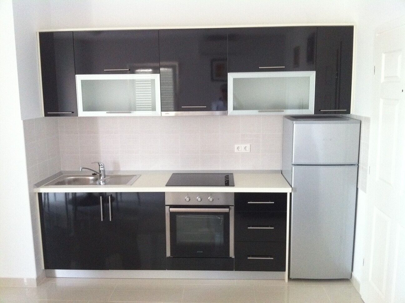 A compact kitchen with black cabinets, a microwave, a stove, and a refrigerator.