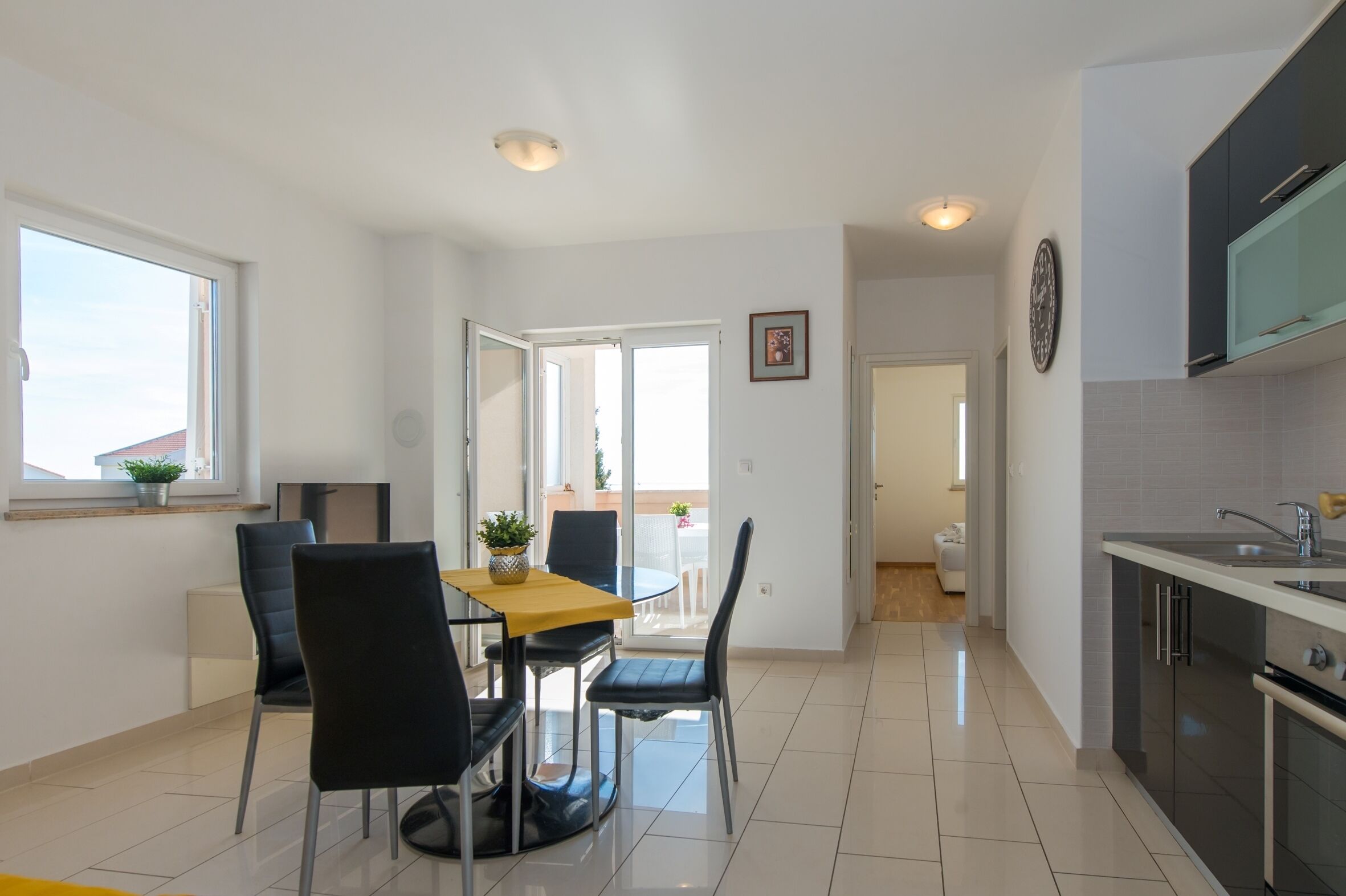 A modern kitchen with a built-in oven and a dining area with a table and chairs.