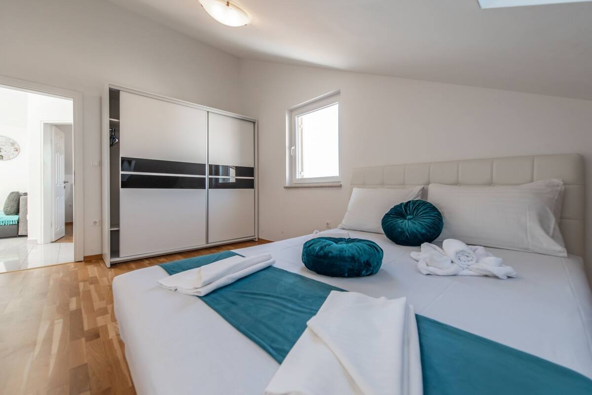 A modern bedroom with a large bed, a wardrobe, and a window.