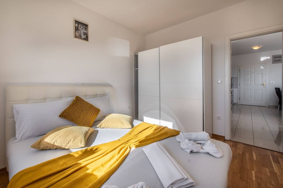 A hotel room with a bed, a wardrobe, and a door leading to another room.