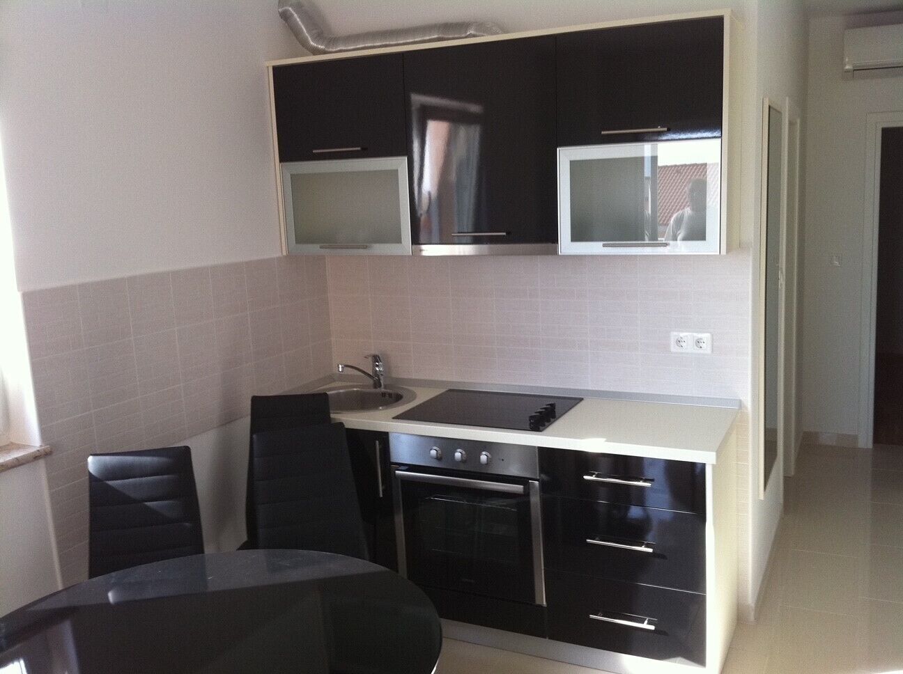 A compact kitchen with a sink, stove, and a microwave above it. There is a dining table with chairs.