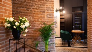 A brick wall, a potted white flower arrangement, a green plant, a staircase, and a room with a table and chairs. - Hotel Teatr  (Kraków)