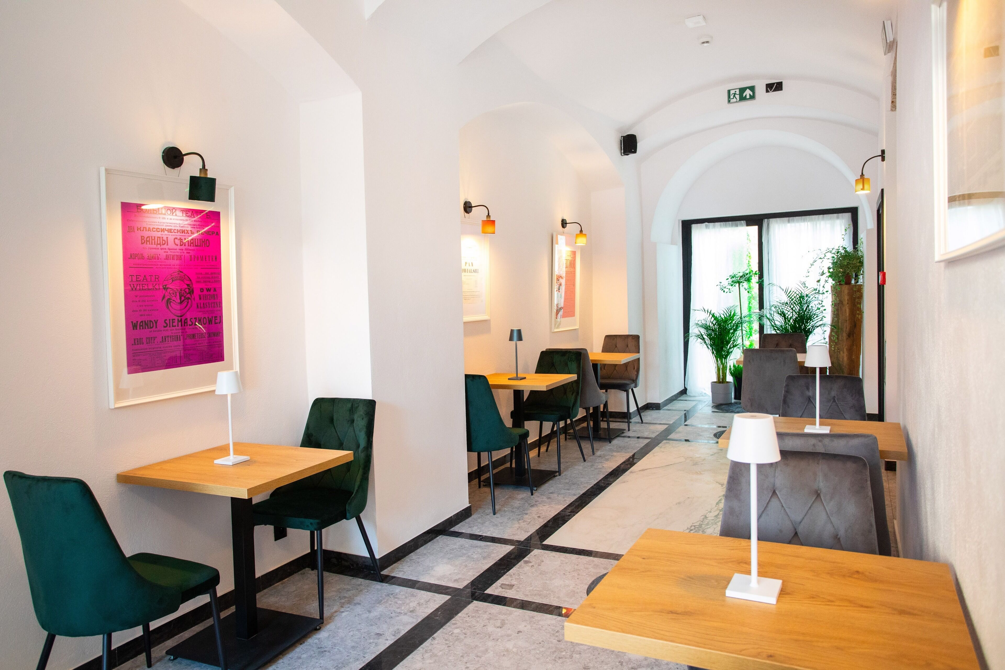 A modern interior with tables and chairs, framed artwork on the walls, and a clear view of the entrance.