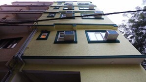 A multi-story building with air conditioning units on the exterior, a visible window, and a door on the ground floor. - Hotel Airport Sinon by Dream Laxmi (New Delhi)