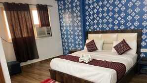A bedroom with a wooden bed, a red and white patterned rug, a blue floral wallpaper, and a window with curtains. - Hotel Airport Sinon by Dream Laxmi (New Delhi)