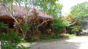 A traditional building with a tiled roof, surrounded by lush greenery and a dirt path. - Hotel O Dannis Homestay Near Musholla Al Istiqomah Terawangan (Narmada)