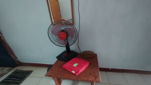 A small room with a table, a fan, and a mat. - Hotel O Dannis Homestay Near Musholla Al Istiqomah Terawangan (Narmada)