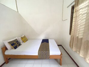 A single bed with a wooden frame, white bedding, and patterned pillows. - Hotel O Sederhana Homestay (Sidoarjo)