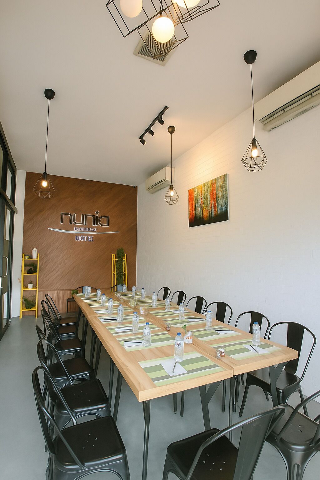Ein Konferenzraum mit einem langen Tisch, Stühlen und einer Holzwand mit einem Schild.