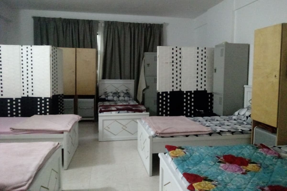 A bedroom with two beds, a wardrobe, and a desk.