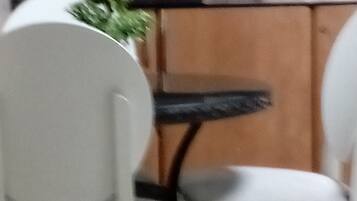 Zona de menjador amb dues cadires blanques i una taula petita rodona.