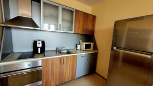A compact kitchen with a stainless steel refrigerator, a microwave, a coffee maker, and wooden cabinets. - 3-room new apartment,  5-min walk to 3 sandy beaches  (Topola Village)