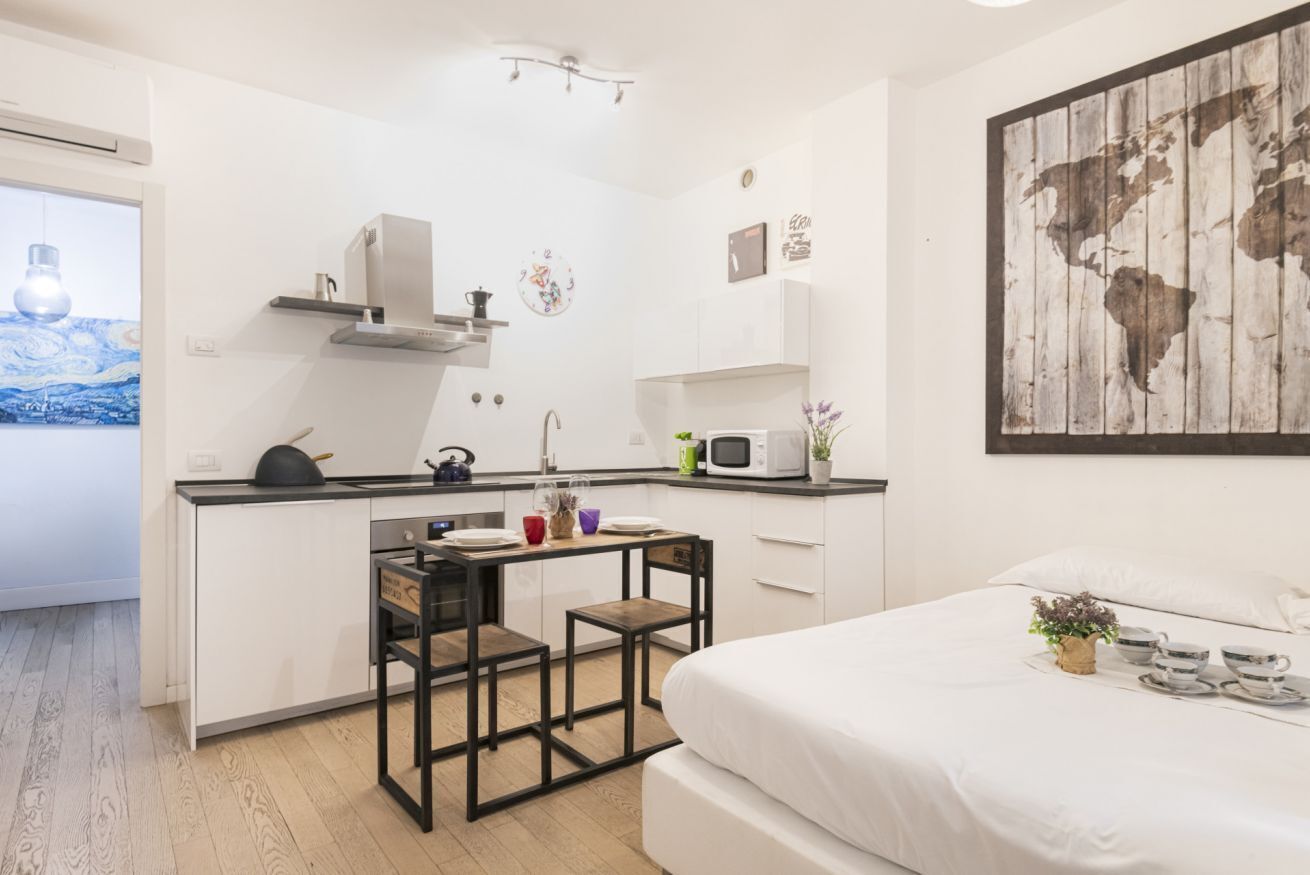 Een compacte hotelkamer met kitchenette, een bed en een wereldkaart als kunstwerk.