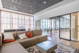 Ein stilvoller Lounge-Bereich mit einer Couch, einem Schild für ein Café und Blick auf den Essbereich.