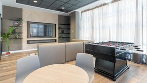 A modern living room with a foosball table, a sofa, and a TV. - Micampus Estrada 11 (Madrid)