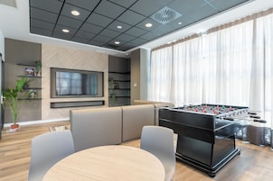 Ein modernes Wohnzimmer mit Kicker, einer Couch und einem Fernseher.