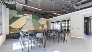 A modern office space with high ceilings, exposed ductwork, and a large abstract mural on the wall. - Micampus Estrada 11 (Madrid)