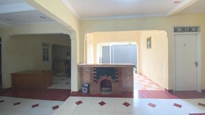 Una habitació àmplia amb terra de rajola, una llar de foc, una porta i una finestra.