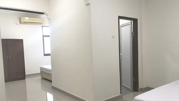 Una habitació amb un llit, un armari, una porta i un aire condicionat.