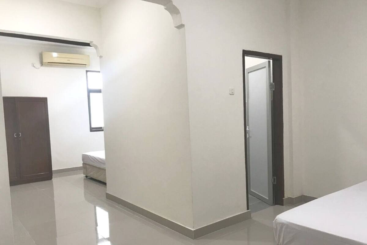 Una habitación con cama, armario, puerta y aire acondicionado.