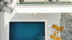 A rooftop pool area with a rectangular pool, two lounge chairs, and a small table with a plant. - Pool apartments Banta A (Novalja)