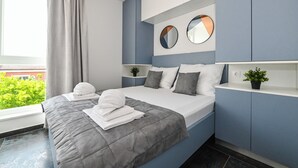 A modern bedroom with a bed, two bedside tables, a large window, and a view of greenery outside. - Pool apartments Banta A (Novalja)