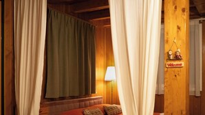 A cozy room with a bed, curtains, a lamp, and a welcome sign.